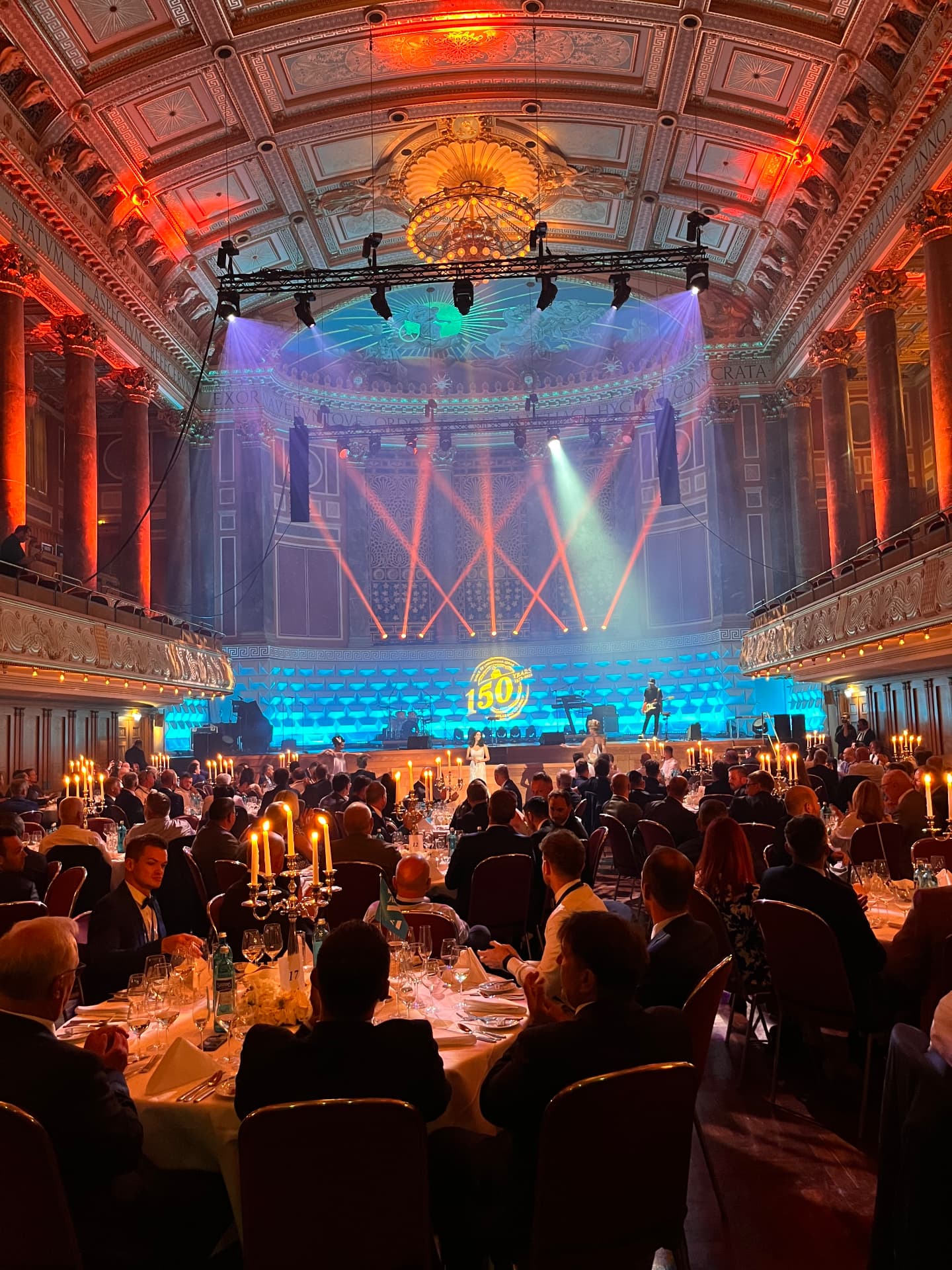 Gemini Music live on stage at a corporate gala dinner, guest tables in the foreground